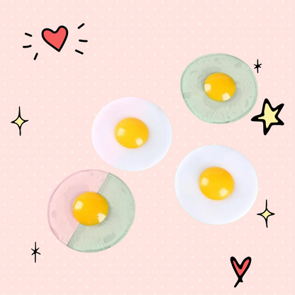 Foundry FitFit egg-shaped squishy fidget toys with clear and white bases and bright yellow yolks on a two-tone background