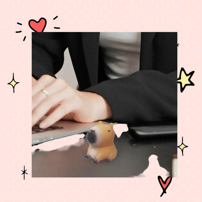 Foundry FitFit capybara squishy sensory toy sitting on a desk next to a person working on a laptop