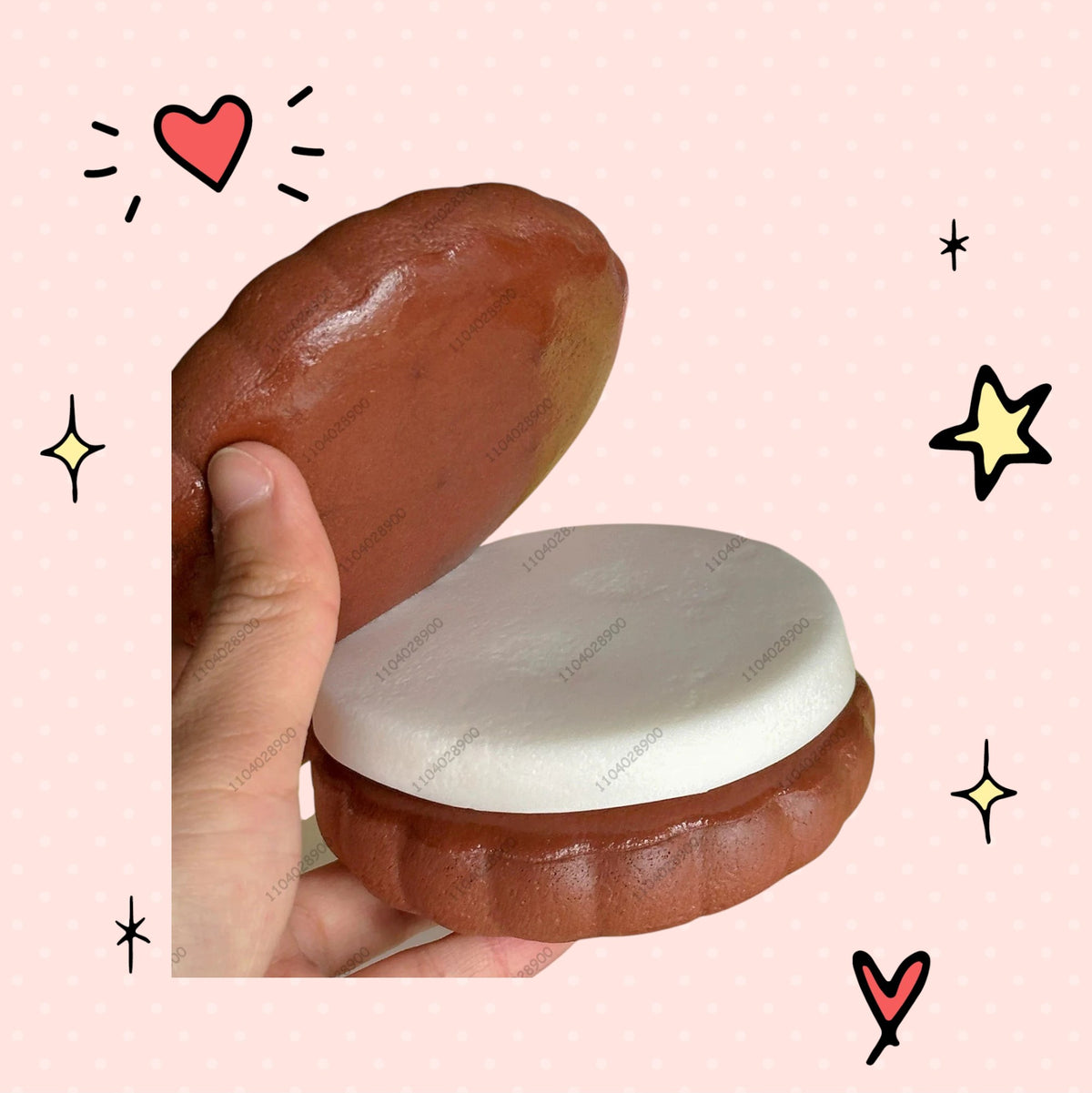 Foundry FitFit chocolate sandwich squishy with a soft white cream center held in hand, surrounded by pastel squishies.