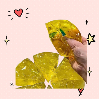 Foundry FitFit yellow honey-drizzled cheese wedge squishy being squeezed, made of soft slow-rise foam for stress relief.