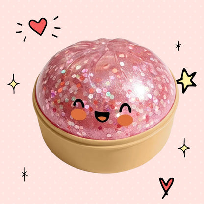Foundry FitFit pink translucent glitter dumpling squishy toy with a cute smiling face in a beige base