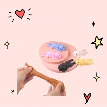 Foundry FitFit kawaii puppy squishies in assorted colors being stretched by hand on a pink display stand